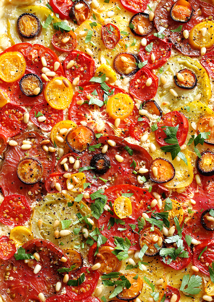 vegan finger food flatbread baked with different kinds of tomatoes olives pine nuts chopped parsley