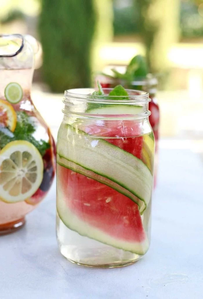 water infused with watermelon cucumber how to detox your body to lose weight glass filled with water large jug in the background