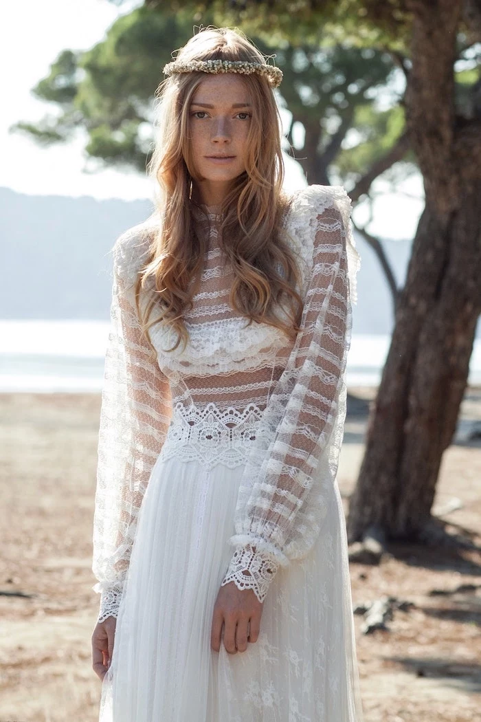 woman wearing long sleeve boho wedding dresses made of lace and tulle with long blonde wavy hair flower crown