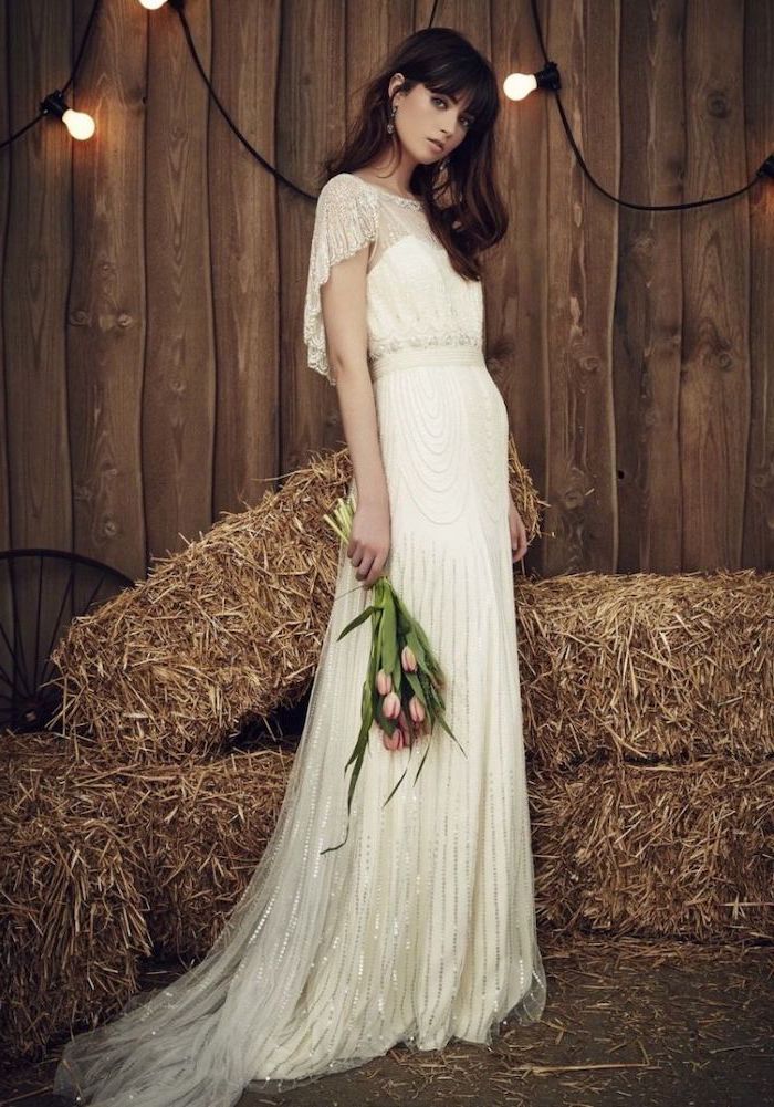 woman wearing white dress made of tulle and lace holding a small pink tulips bouquet boho beach wedding dress with short sleeves