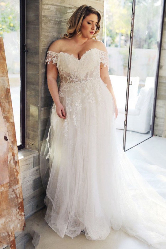 woman with medium length blonde curly hair wearing white dress with bottom skirt made of tulle lacy top plus size boho wedding dress