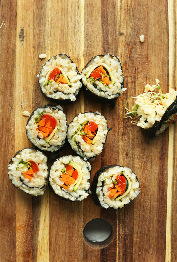 wooden cutting board best vegan appetizers vegan sushi with sprouts brown rice tomatoes carrots inside