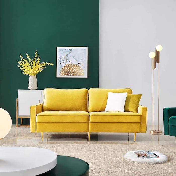 yellow velvet sofa half green half white accent wall behind it mid century modern furniture white carpet on tiled floor