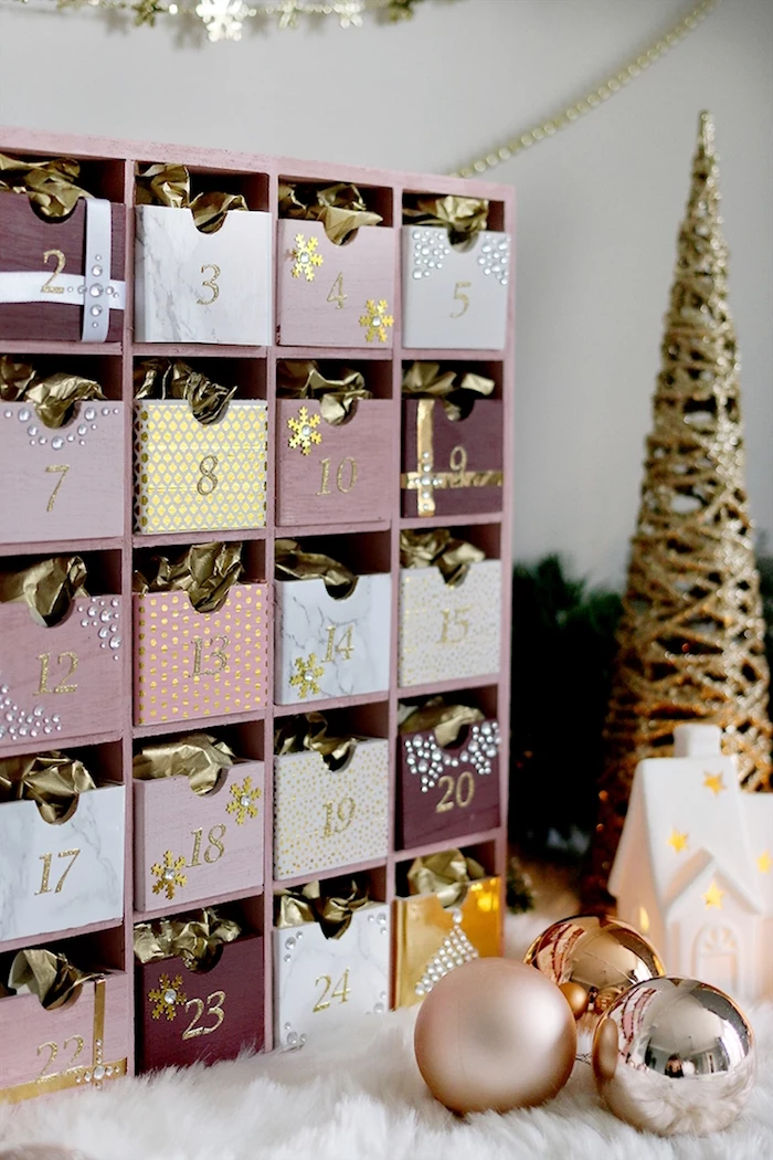 advent calendar in pink purple white and gold diy advent calendar ideas placed next to small faux golden christmas tree and baubles