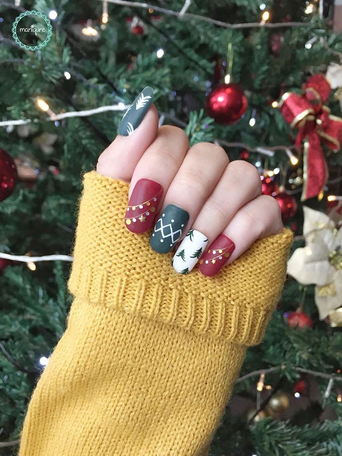 baubles on christmas tree in the background holiday nail designs in red white green matte nail polish with christmas inspired decorations
