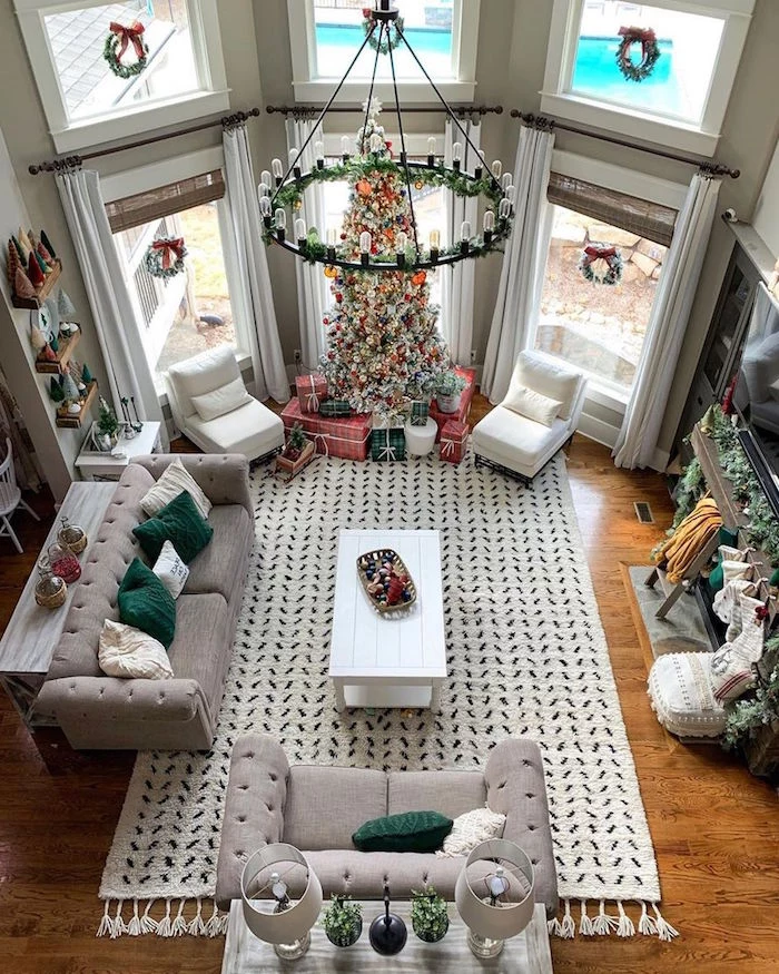 big living room with tall christmas tree decoration ideas lots of presents underneath on white carpet next to tall windows