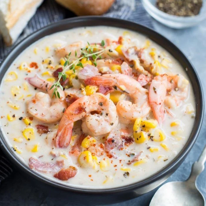 black bowl filled with creamy soup with corn shrimp bacon how to cook raw shrimp garnished with thyme
