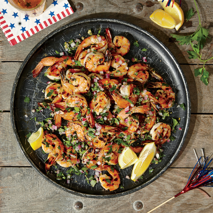 black ceramic plate with herbed grilled shrimp garlic shrimp recipe garnished with chopped parsley onion lemon wedges