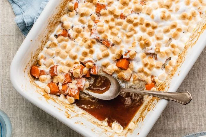 candied yams covered with marshmallows baked in white casserole dish best thanksgiving sides spoon on the side