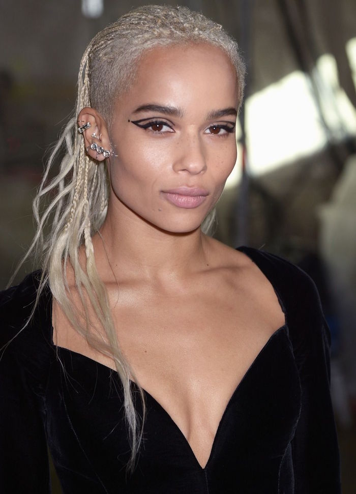 cat eye makeup zoe kravitz with blonde hair lots of ear piercings wearing black velvet dress with deep v neckline