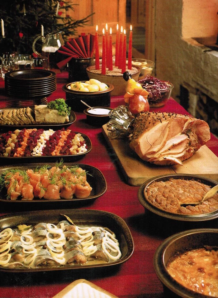 christmas eve dinner ideas table with red table cloth different dishes on the table in black trays and plates baked ham on wooden cutting board