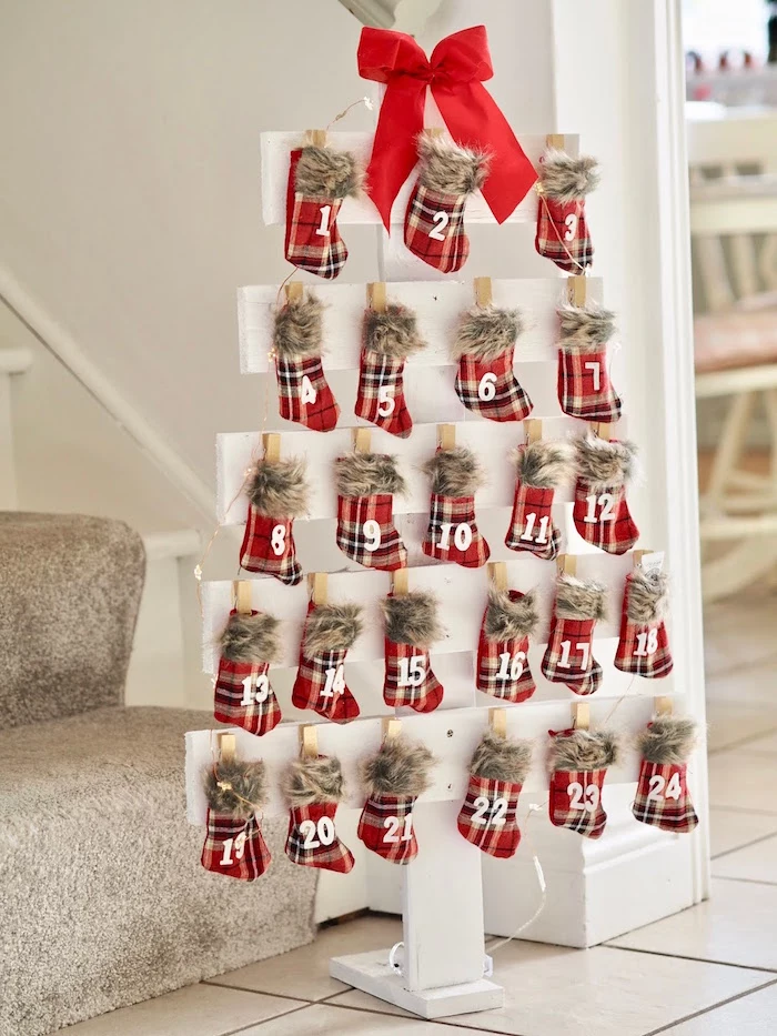 christmas stockings hanging from white wooden boards arranged in the shape of christmas tree advent calendar ideas