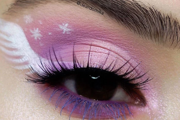 close up photo of brown eye with thick eyebrows winged eyeliner tutorial with purple eyeshadow white wing drawn on the side of the eye