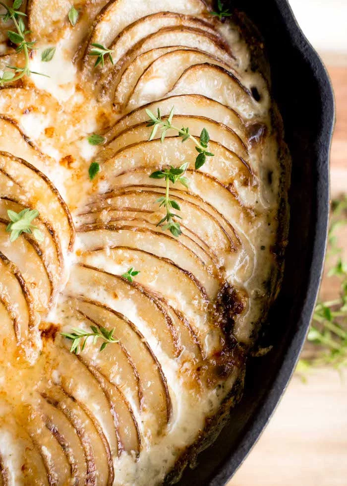 close up photo of creamy potatoes au gratin best thanksgiving side dishes baked in black skillet