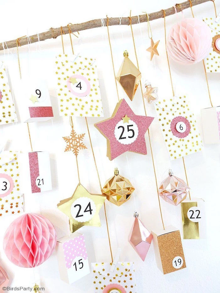 close up photo of homemade advent calendar boxes hanging with white and gold strings from small wooden branch