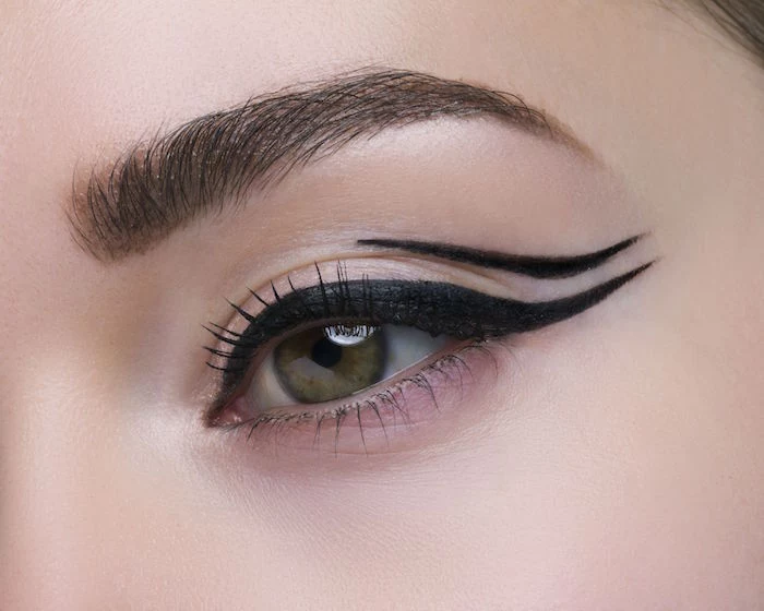 close up photo of woman with green eyes dark brown eyebrows cat eye eyeliner negative space eyeliner with two lines
