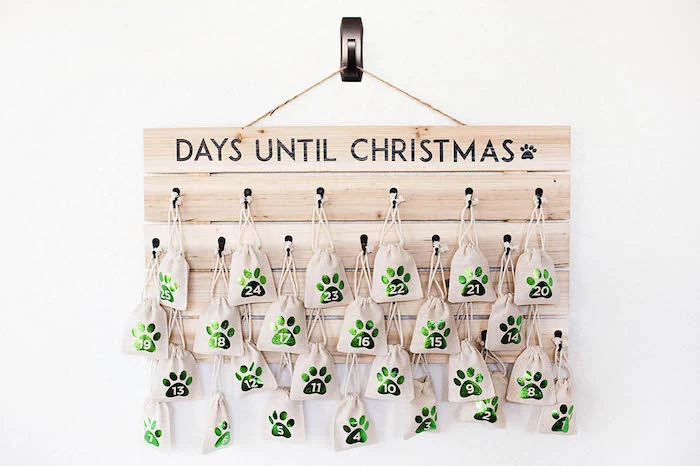 days until christmas written on wooden board hanging on white wall advent calendar small bags hanging decorated with numbers from one to twenty five