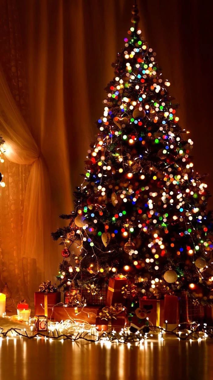 decorated christmas tree with lots of colorful lights merry christmas wallpaper presents underneath the tree