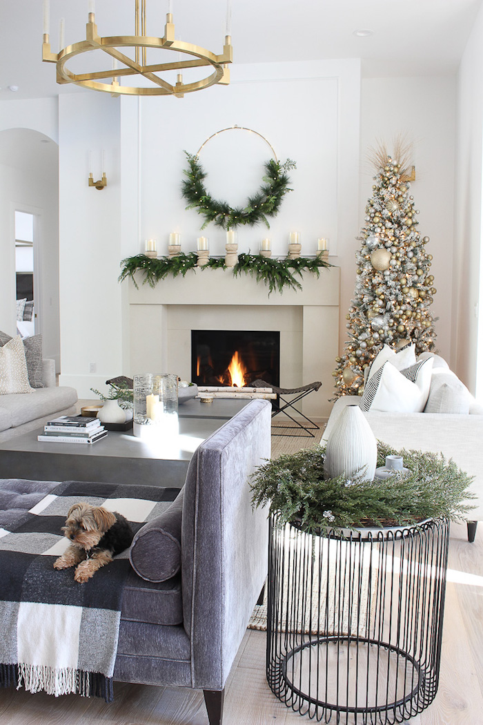 dog on gray sofa white christmas tree decorations small tree next to fireplace with silver and gold ornaments and baubles