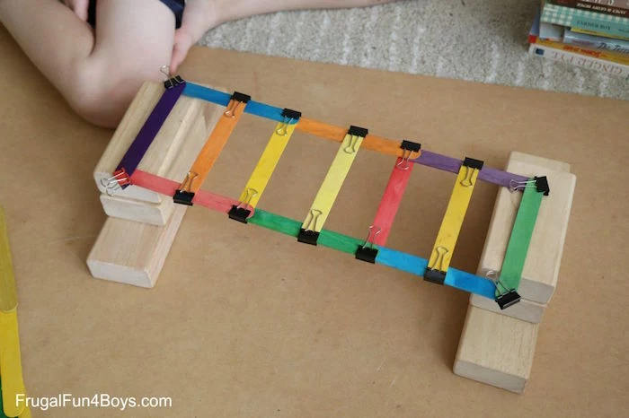 fun things to do with kids bridge built out of popsicle stickes painted in different colors on wooden blocks