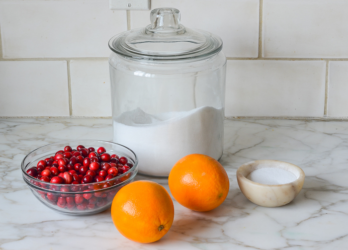 glass bowl with cranberries two lemons sugar christmas ham dinner cranberry sauce ingredients arranged on marble countertop