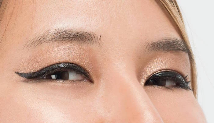 gold eyeshadow black eyeliner on woman with brown eyes blonde hair how to do a cat eye close up photo