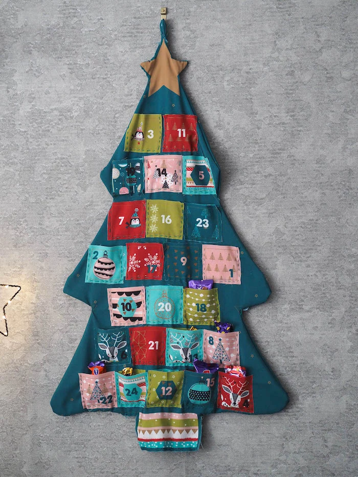 gray wall christmas countdown calendar made of fabric with small pockets in different colors filled with candy