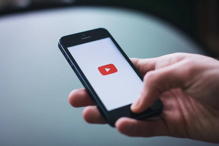hand holding phone opening youtube on the phone youtube channels icon on white background