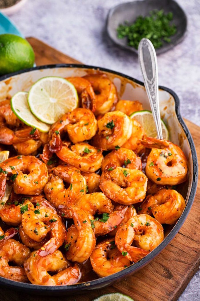 how to cook frozen shrimp honey lime shrimp cooked in skillet spoon and lime slices on the side placed on wooden cutting board