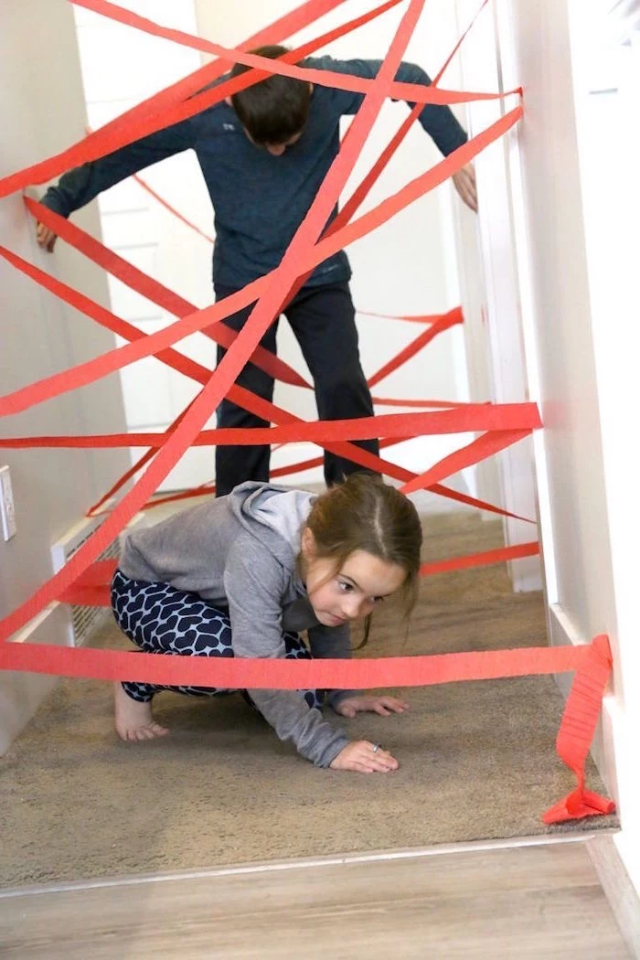 little boy and girl going through a hallway with red crepe paper attached to the walls activities for kids at home