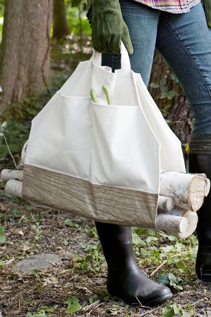 log carrier made from white fabric carried by woman wearing jeans black rubber boots and green mits good gifts for dad