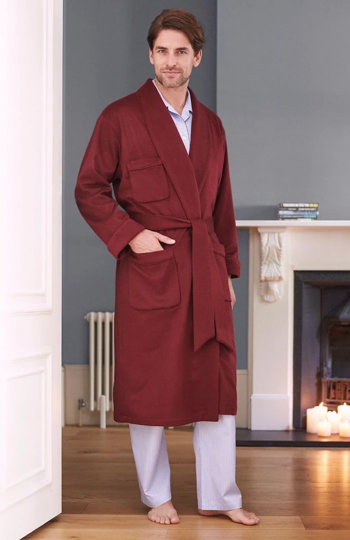 man standing next to fireplace on wooden floor gifts for dad from daughter wearing white pyjamas and red robe