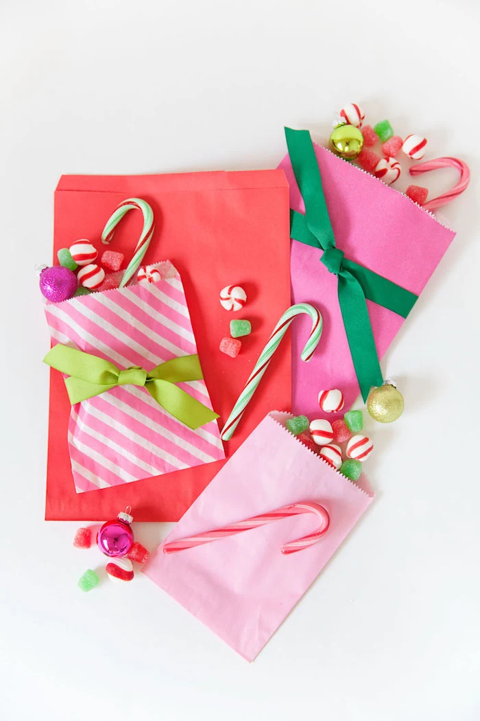 paper bags in pink and red filled with candy unique advent calendars tied with green ribbons placed on white surface