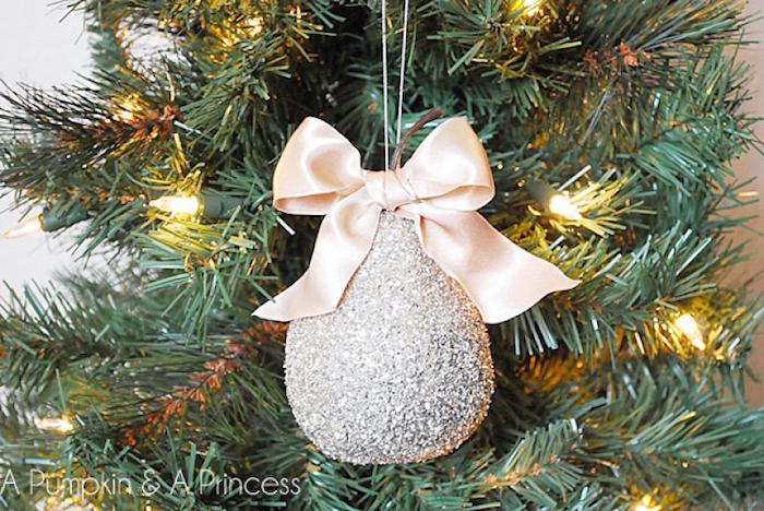pear shaped ornament with beige bow covered with silver glitter christmas tree decorations 2020 hanging from tree with lights