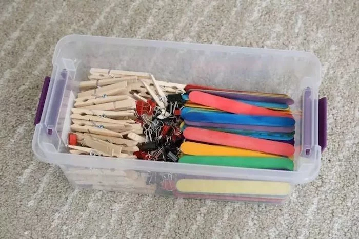 plastic container filled with clothespins fun things to do with kids popsicle sticks painted in different colors