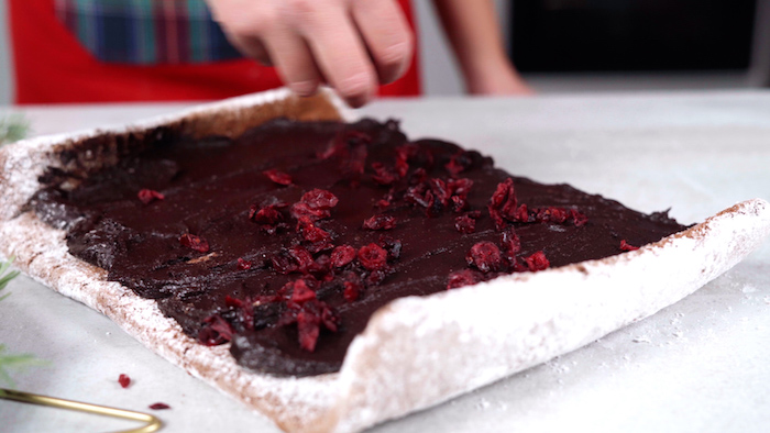 putting hazelnut spread and dried cranberries on batter christmas party food ideas buffet covered with powdered sugar