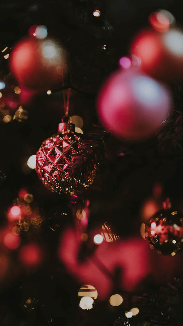 red baubles hanging on decorated christmas tree with fairy lights christmas wallpaper computer close up photo