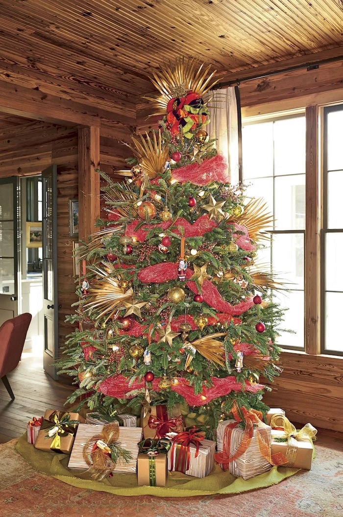 red ribbon around tree with palm leaves painted in gold presents underneath white christmas tree decorations green rug