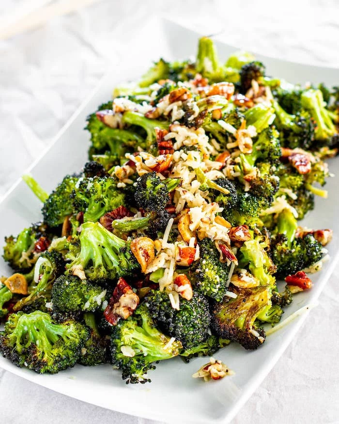 roasted broccoli with cheese walnuts placed on white plate what to make on thanksgiving placed on white surface