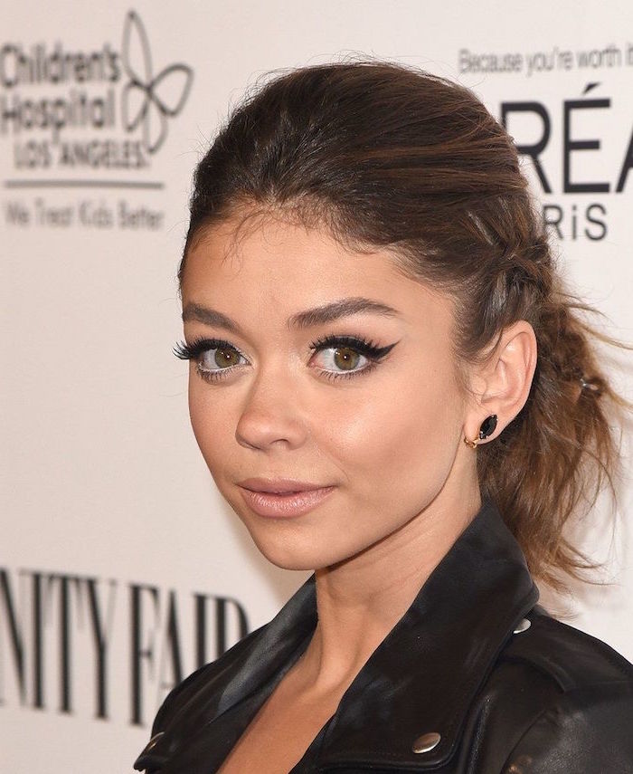 sarah hyland on the red carpet wearing black leather jacket hair with two side braids black earrings winged eyeliner