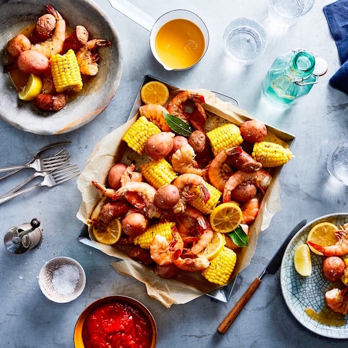 shrimp potatoes and corn on the cob placed inside baking sheet how to cook shrimp garnished with lemon slices