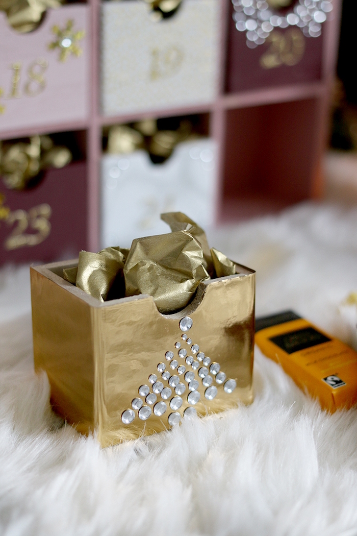 small wooden box painted in gold decorated with rhinestones filled with candy and gold paper christmas tree advent calendar