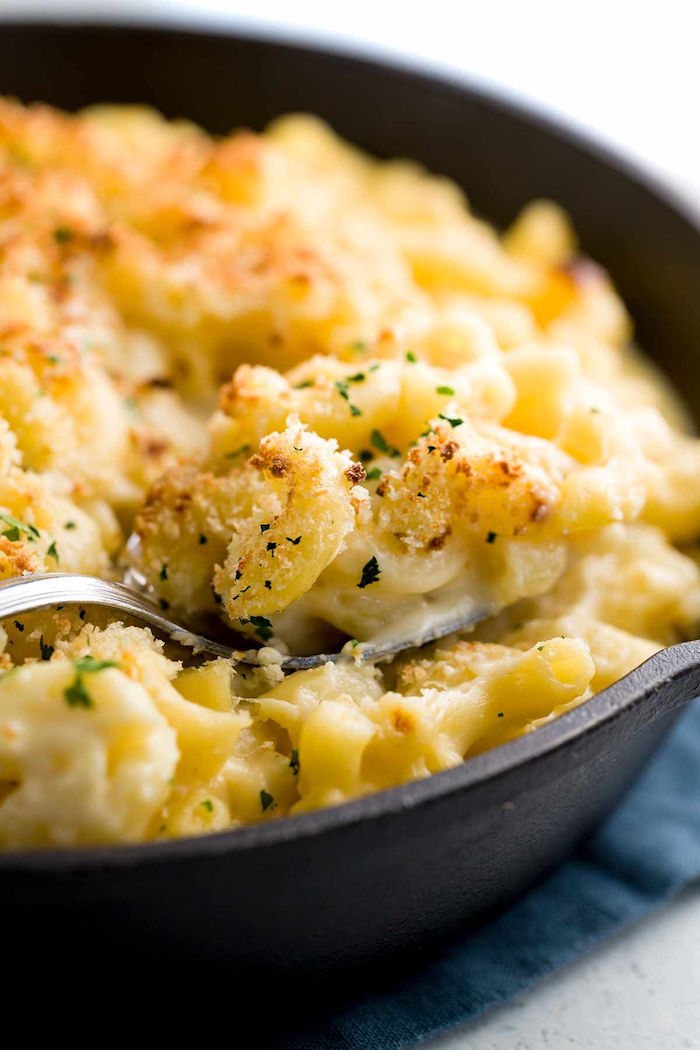 spoonful of baked mac and cheese with panko crumbs and chopped parsley easy christmas dinner menu cooked in black skillet