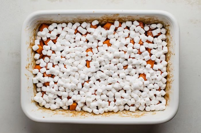 sweet potatoes cut into cubes placed in white casserole dish best thanksgiving sides covered with marshmallows