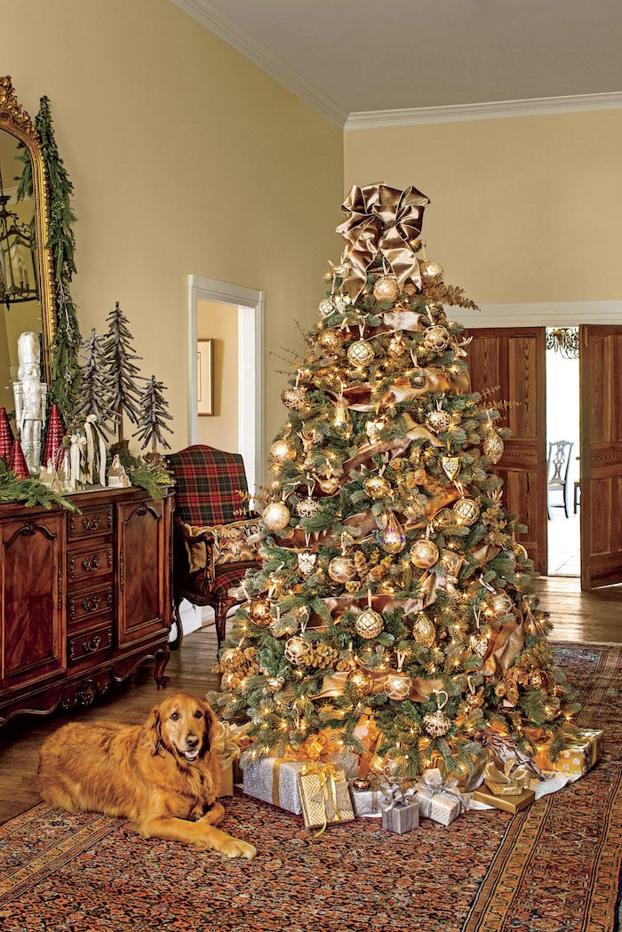 tall tree with lots of gold baubles and ornaments presents underneath how to decorate a christmas tree placed in a hallway