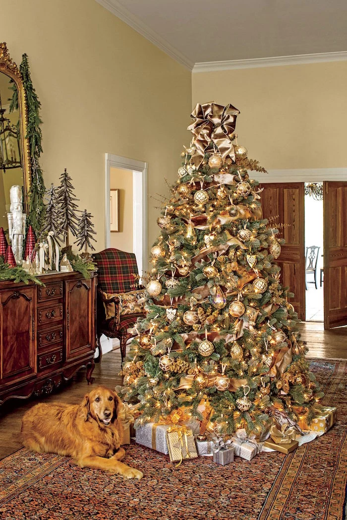 tall tree with lots of gold baubles and ornaments presents underneath how to decorate a christmas tree placed in a hallway
