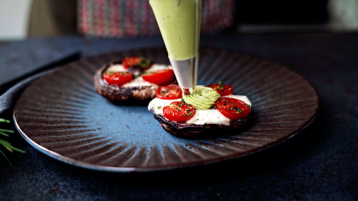 thanksgiving side dishes 2020 two portobello mushrooms stuffed with baby mozzarella cherry tomatoes placed on black and blue plate