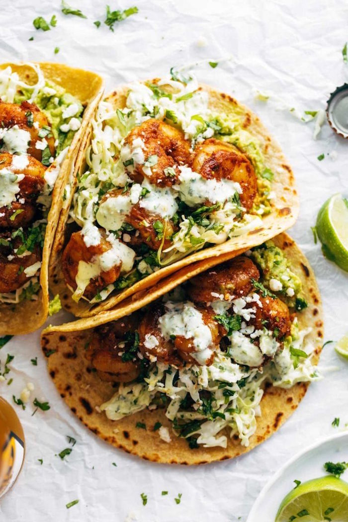 three tacos arranged on white paper baked shrimp recipes shrimp with guacamole chopped cabbage creamy sauce on top