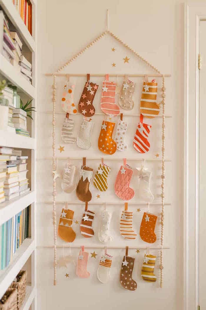unique advent calendars stockings in different colors hanging from wooden rack hanging on white wall