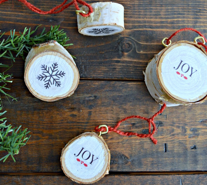 unique christmas ornaments birch wood ornaments painted white joy written on them with snowflakes arranged on wooden surface